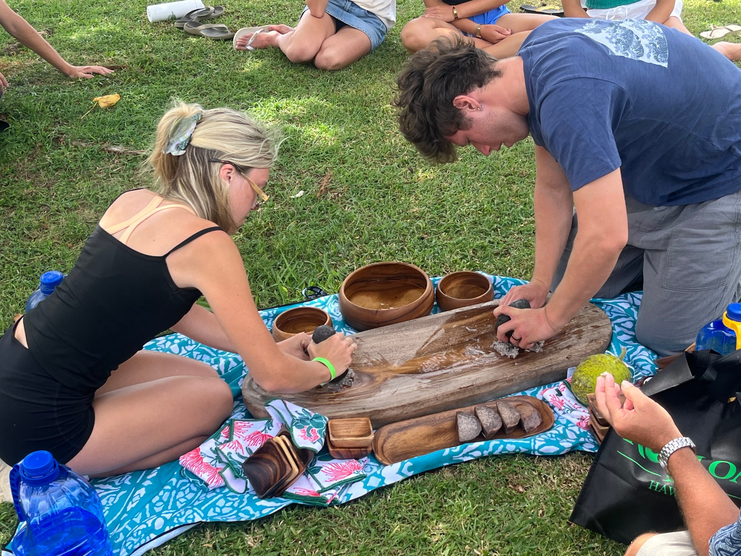 Group preparing banana stalks and leaves beside a smoking fire pit