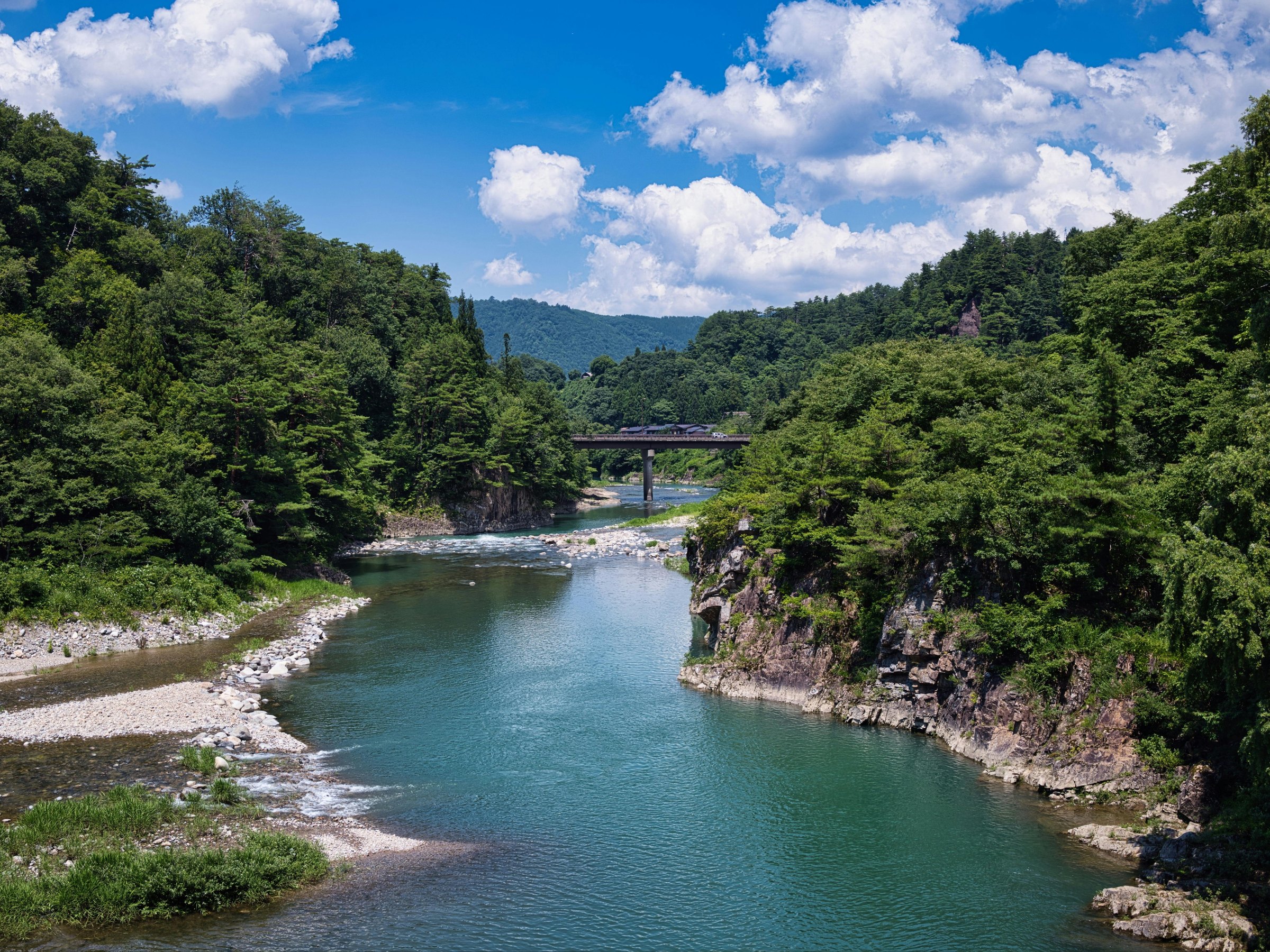 Clear river winding through forested hills under a blue sky