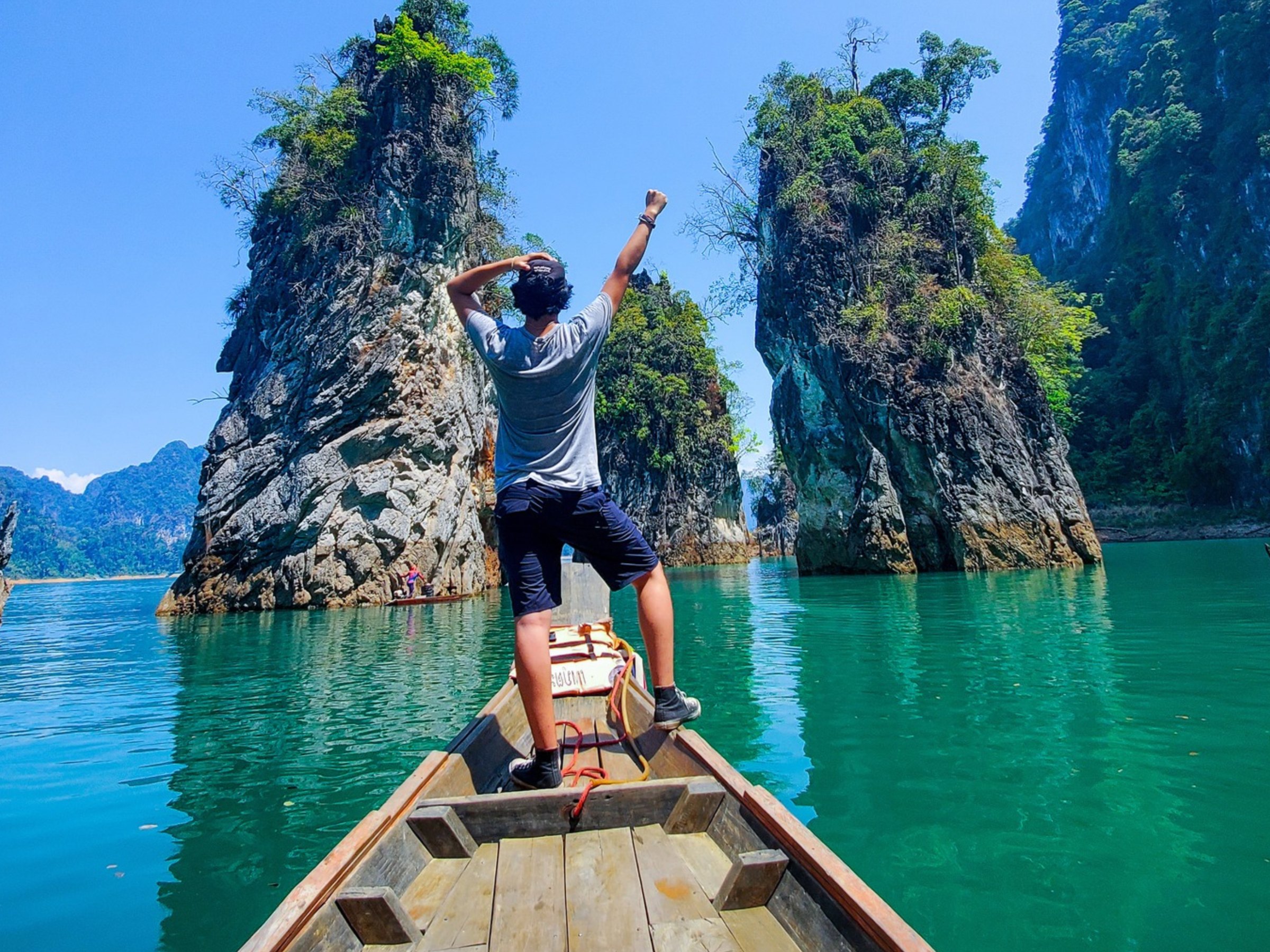 Student standing at the bow of a longtail boat between limestone rocks