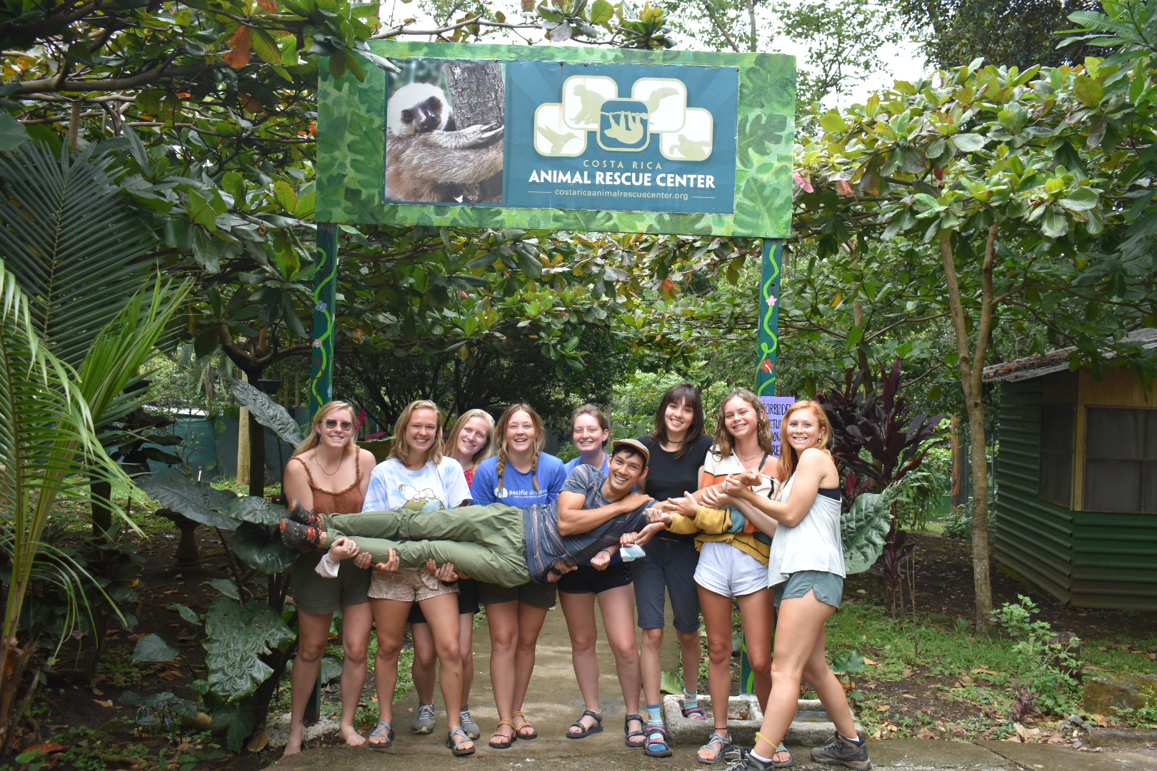 Group of students in matching T-shirts outside a wooden shelter
