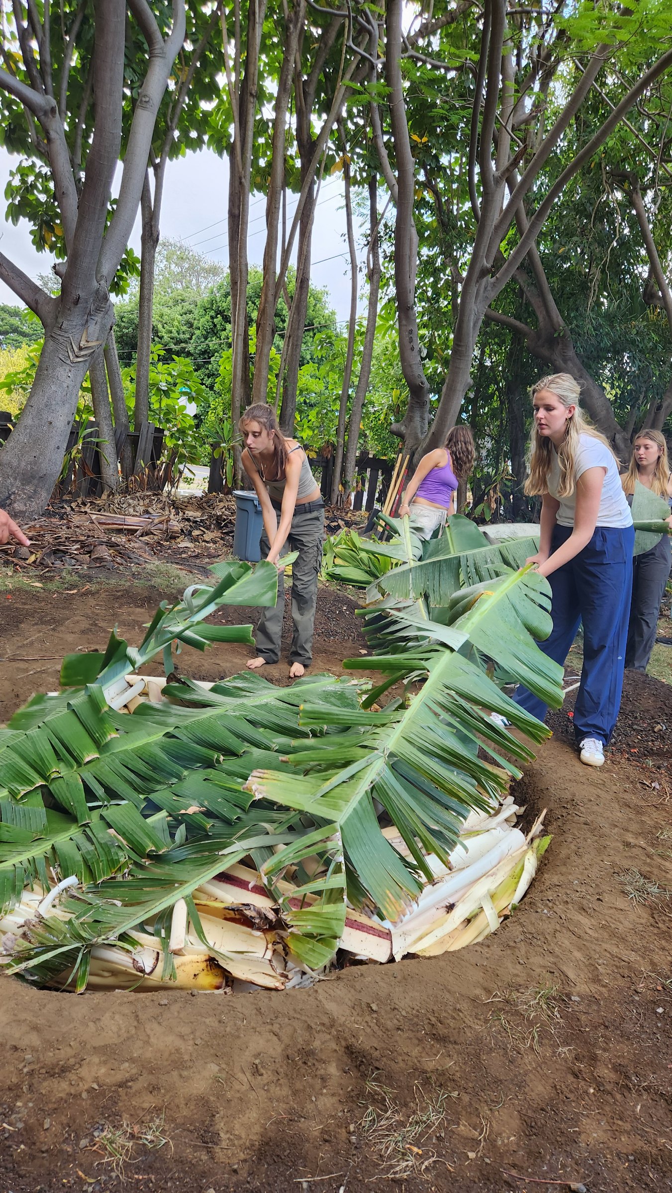 Group of students holding buckets and litter grabbers on a sandy beach