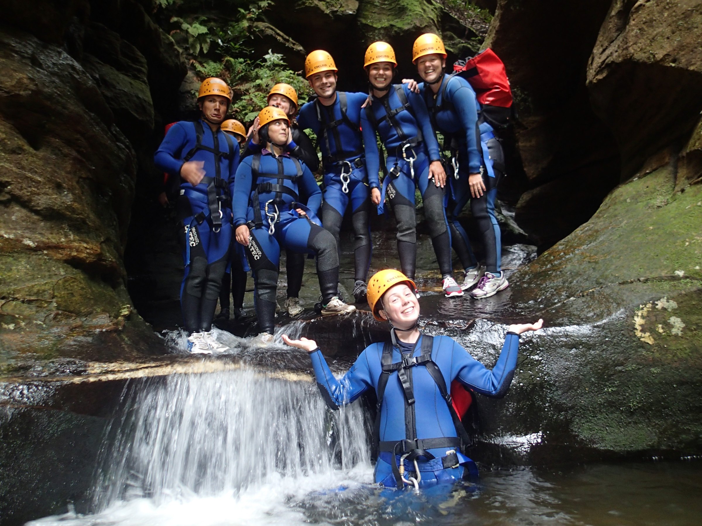 Student abseiling down a rock face above a forested valley