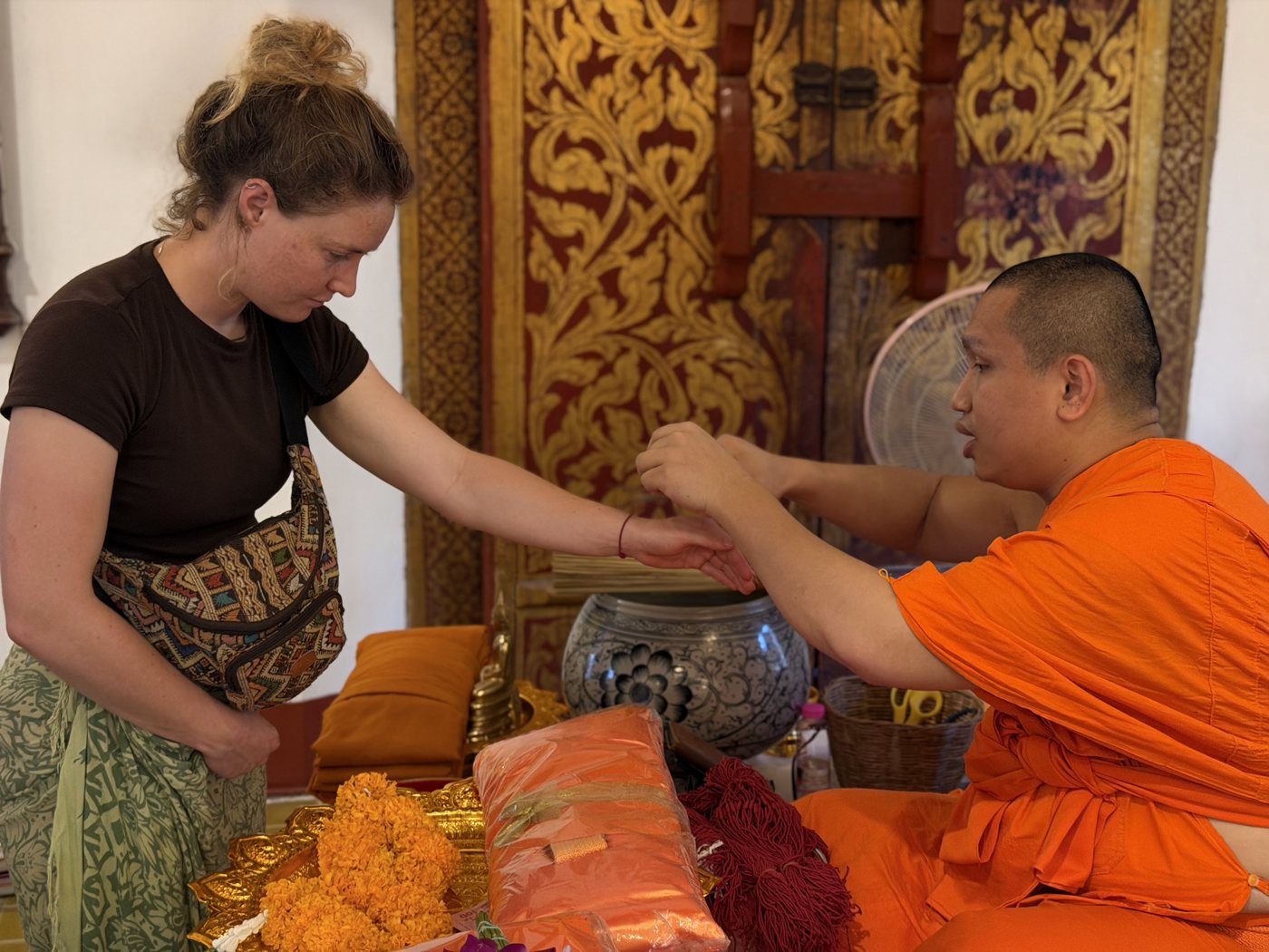 Monk tying a blessing string on a student’s wrist