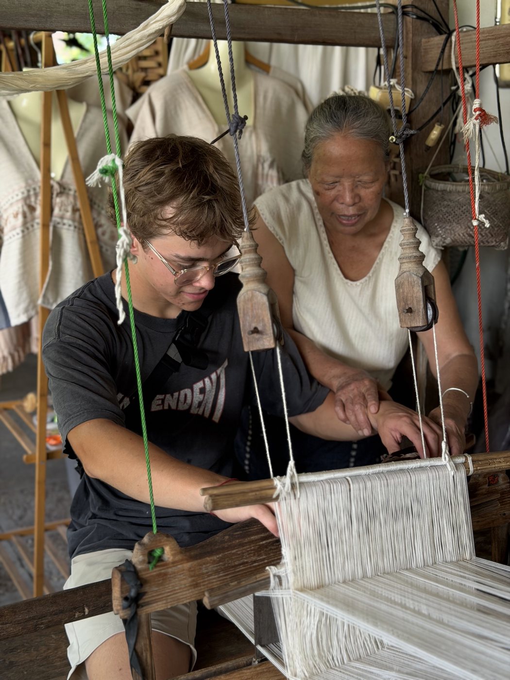 Local weaver guiding a student at a loom